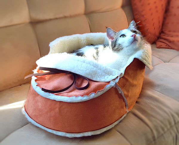 Sherpa Moccasin Cat Bed in Orange with a cat snuggling in it
