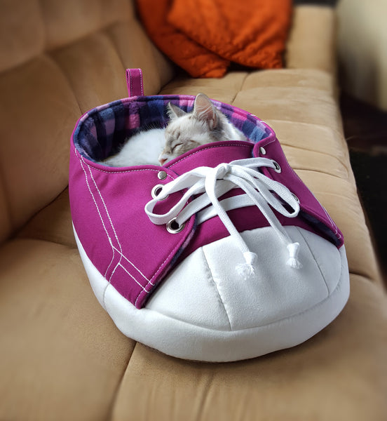 A cat sleeping inside of Purple Sneaker Pet Bed