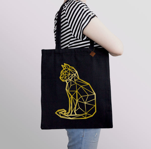 carrying a black tote bag with gold cat print