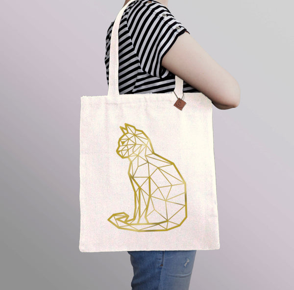 carrying a beige tote bag with gold cat print