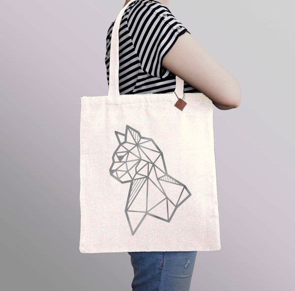 carrying a beige tote bag with silver cat print