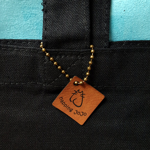 close-up of faux leather logo tag and chain